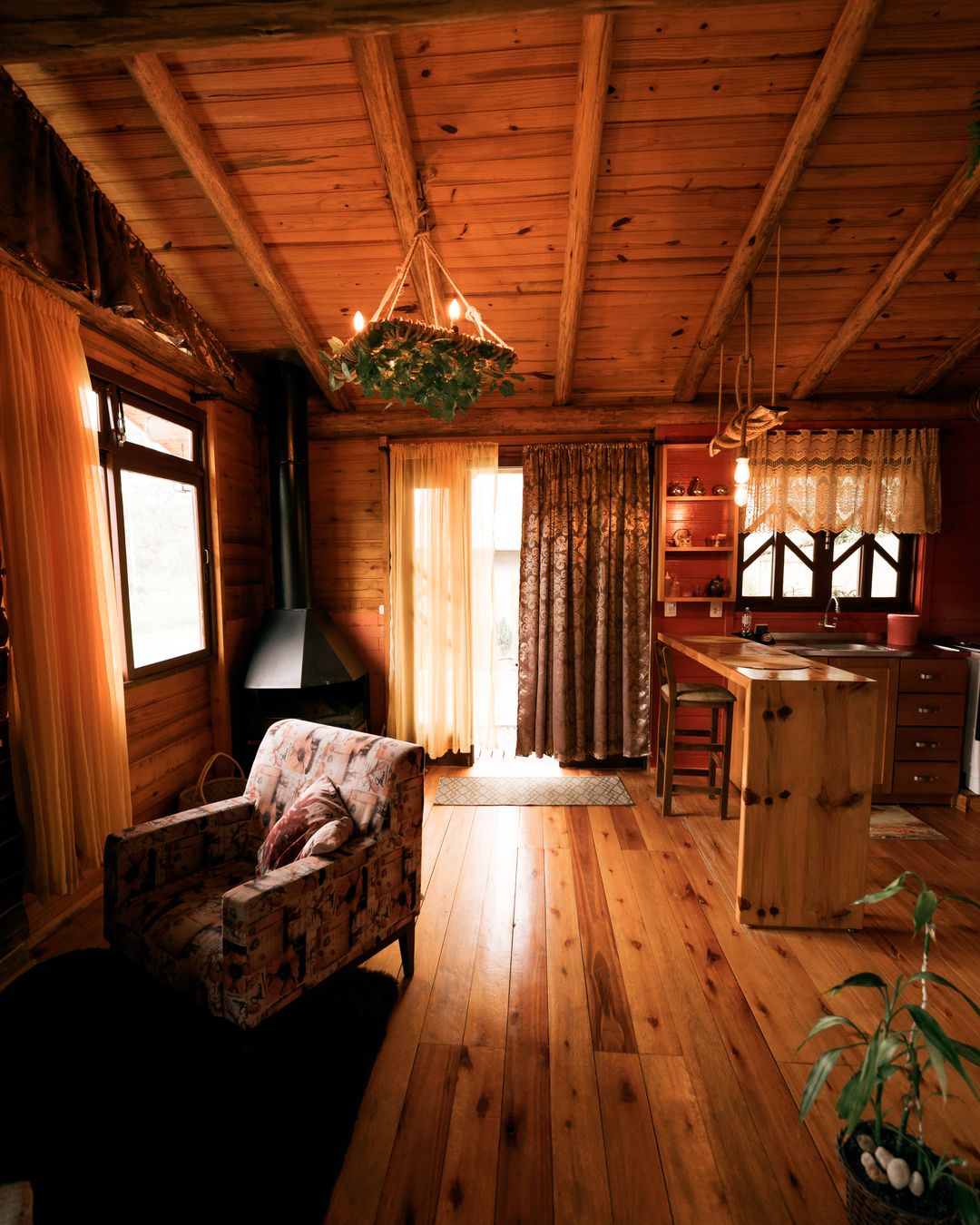 Sala de estar da cabana Patchouli com poltrona e cozinha ao fundo