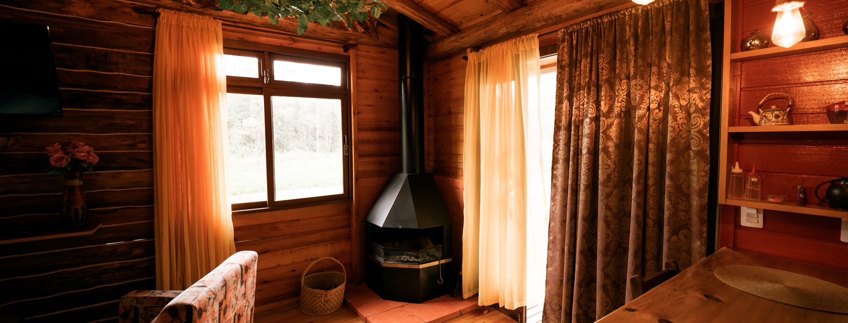 Lareira de canto e cortinas na cabana Patchouli